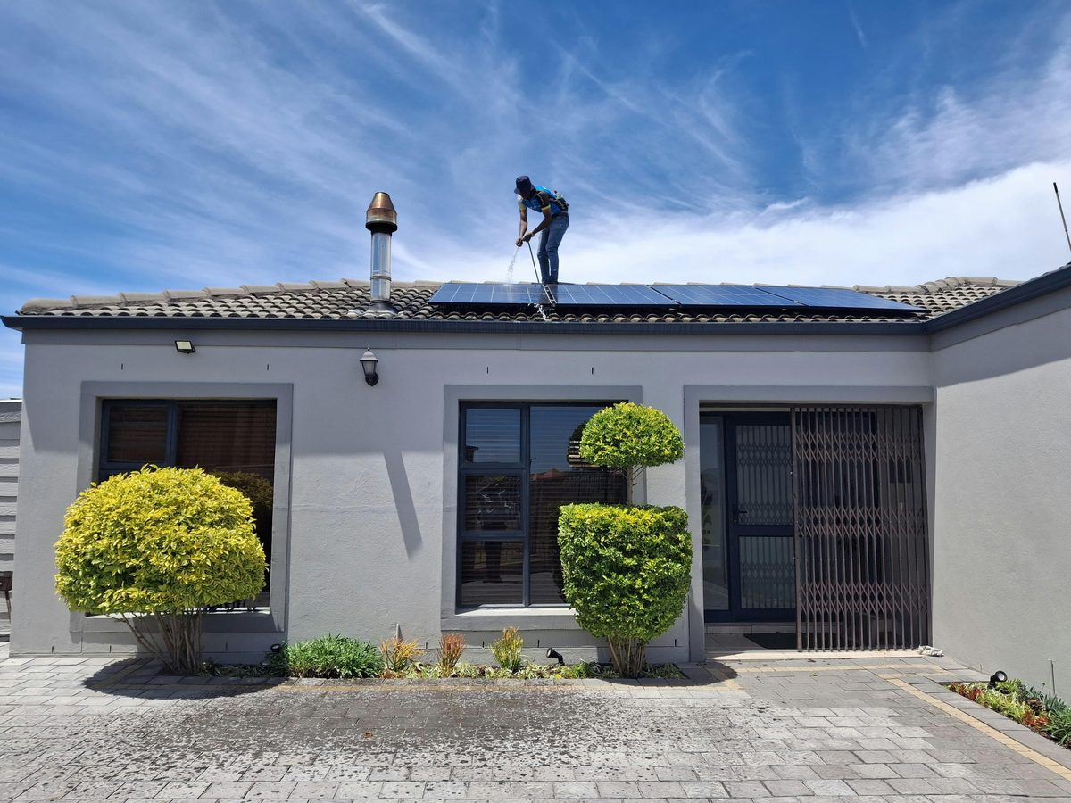 Worker cleaning rooftop solar panels - Good Taste Cleaning Services